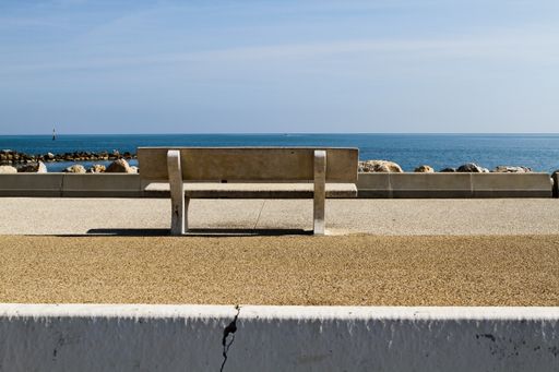 A closeup shot of a bench in a beach boulevard on a sunny day