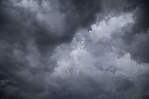 A low angle greyscale of a dark cloudy sky in the evening - perfect for backgrounds and wallpapers