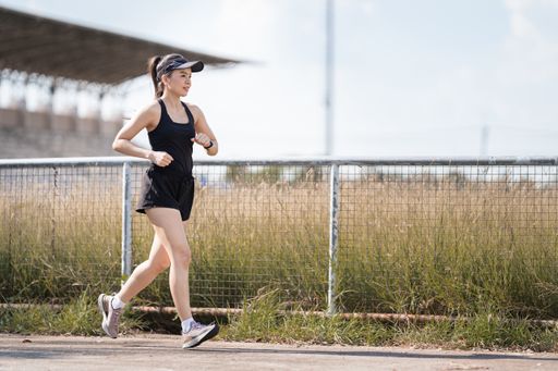 A healthy happy Asian runner in a black outfit jogging in a park during the sunset