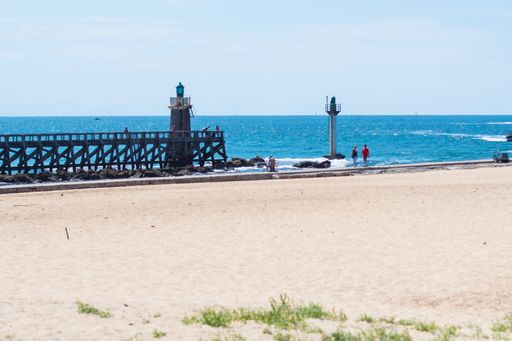 A high angle shot of the seascape with a small lighthouse on the beach in the foreground