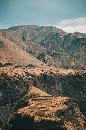 A vertical shot of hills covered in greenery under a blue sky in the countryside