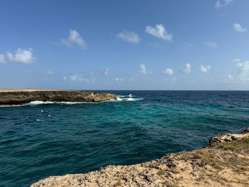 A scenic coastal view with turquoise waters and rocky cliffs under a clear blue sky, capturing the beauty of nature.