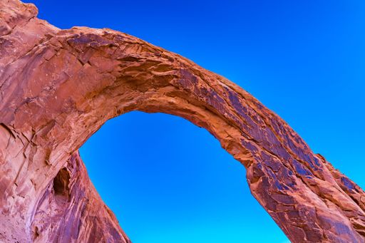 Natural rock arch against a vibrant blue sky in Arches National Park, Utah, showcasing the stunning geological formations.