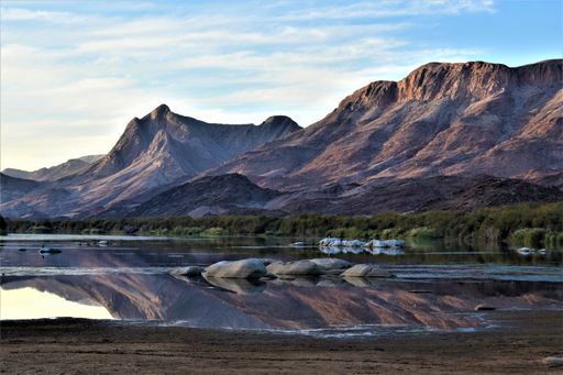 The beautiful scenery of rocky mountains and a lake with reflections in the water under a blue sky