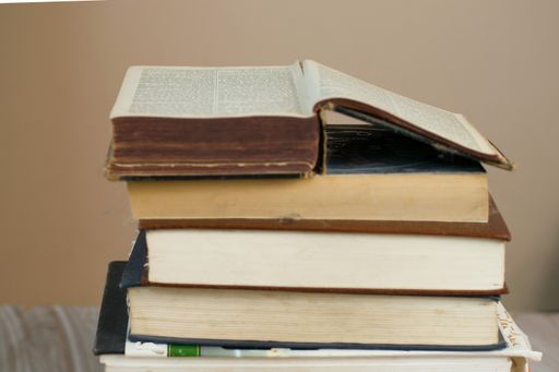 A closeup shot of a stack of old dusty books with a beige background