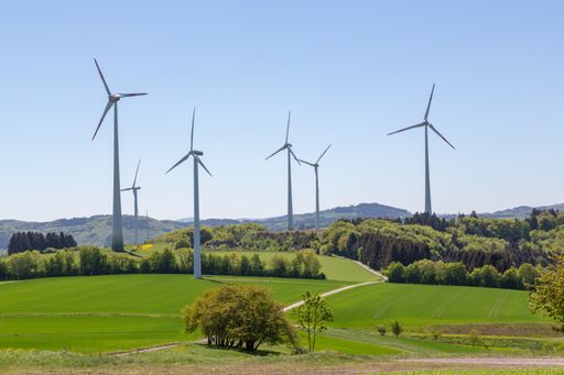 A field with wind power generators under the blue sky