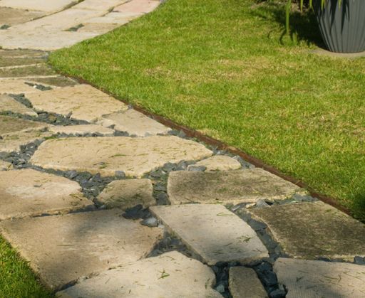 A closeup shot of a stone path next to the green grassy ground