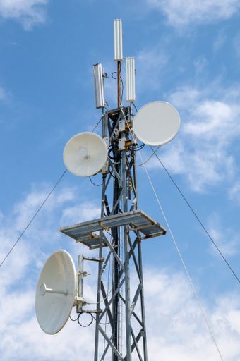 A verticals shot of a telecom antenna against a cloudy sky