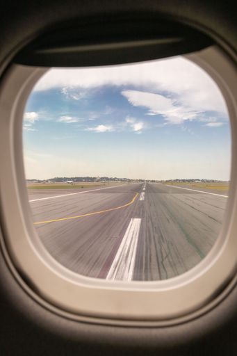 View from airplane window showing runway and clear sky, capturing the anticipation of takeoff.