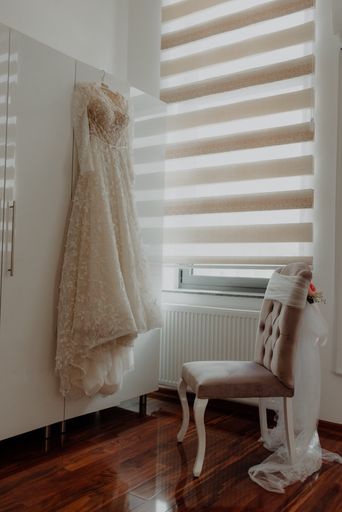 The bride's wedding dress hanging against a white cabinet in a room