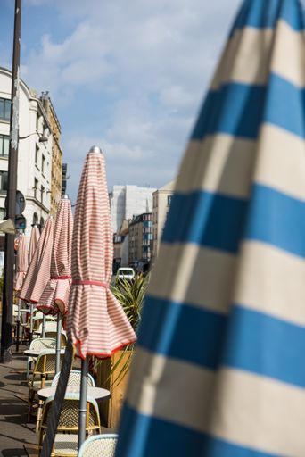 a vertical shot of a cafe with closed umbrellas on a street in France