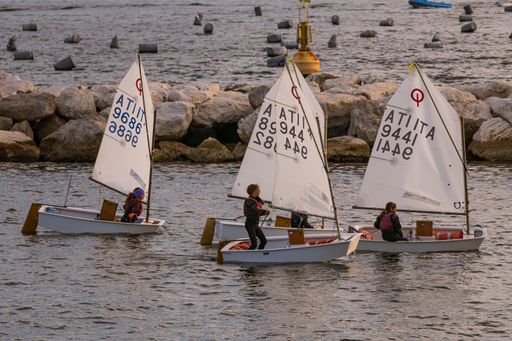 A delightful scene of small sailboats captured from the port of Naples, likely part of a sailing school for children and teenagers