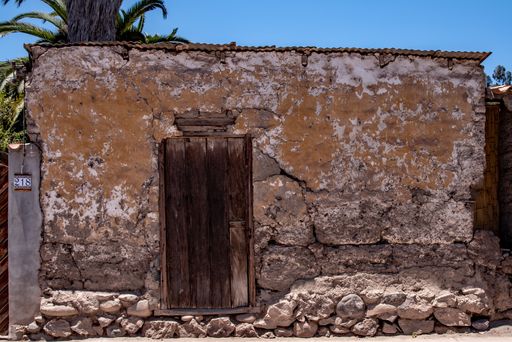 A vertical shot of an old wooden door in an ancient building under the sun