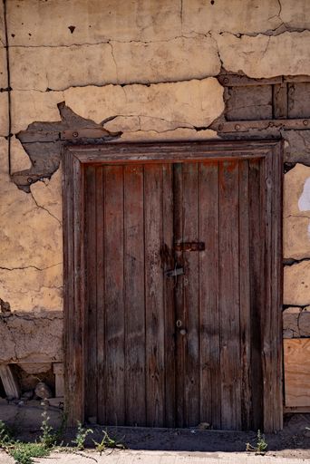 A vertical shot of an old wooden door of an ancient building under the sun