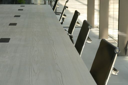 A closeup of a meeting table with empty black seats.