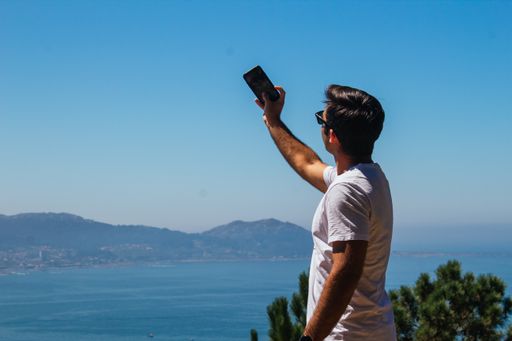 A young Spanish Caucasian man taking a selfie with his phone, outdoors on a hike