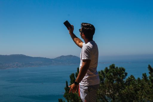 A young Spanish Caucasian man taking a selfie with his phone, outdoors on a hike
