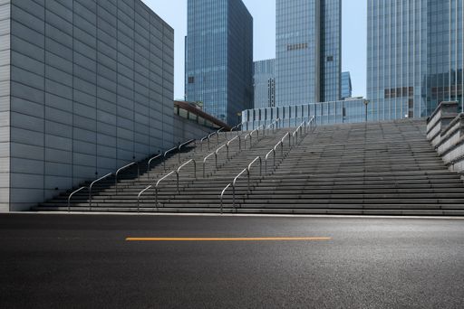 An asphalt road and wide steps leading to modern office buildings at an urban area
