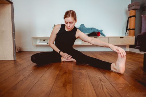 A beautiful shot of a Caucasian girl wearing sportswear and doing yoga at home