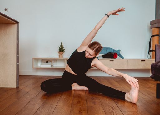 A beautiful shot of a Caucasian girl wearing sportswear and doing yoga at home