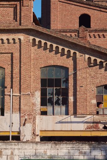 A vertical shot of an abandoned building exterior with broken windows