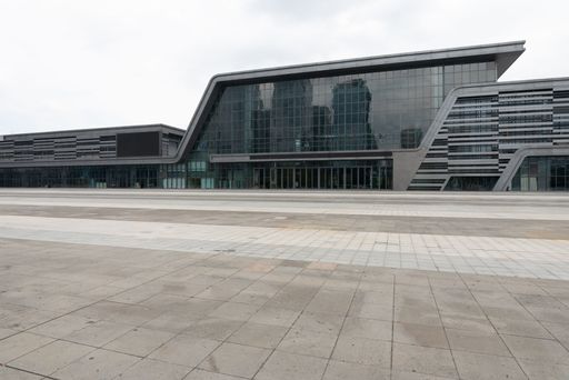 Modern architectural building with sleek glass facade and geometric design, set against a cloudy sky.