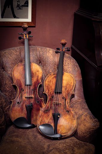 Detail of a pair of violins resting on an old sofa in the luthier's workshop