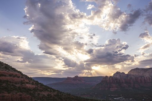 A dramatic sunset over Sedona's red rock formations with sunbeams piercing through clouds