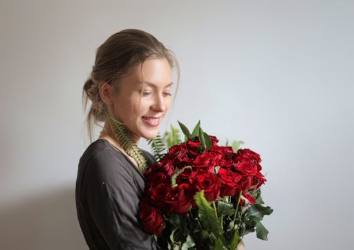 A portrait of a cheerful Hungarian woman holding a bouquet of red roses