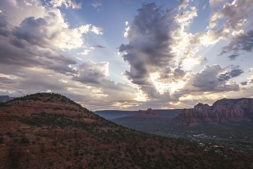 Scenic view of Sedona's red rock formations under a dramatic sky at sunset.