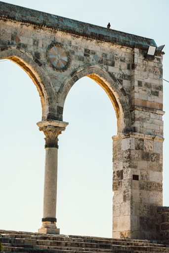 Historic stone archway with intricate details under a clear sky, showcasing ancient architecture.
