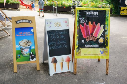 A shot of advertising boards of three different Polish ice-cream brands placed on the ground in Park Cytadela