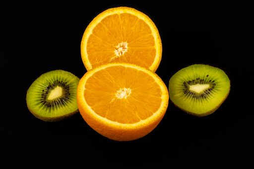 A closeup shot of fresh sliced orange and kiwi isolated on a dark background