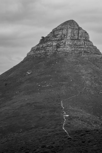 Black and white photo of Lion's Head in Cape Town, showcasing its distinct shape under a cloudy sky.