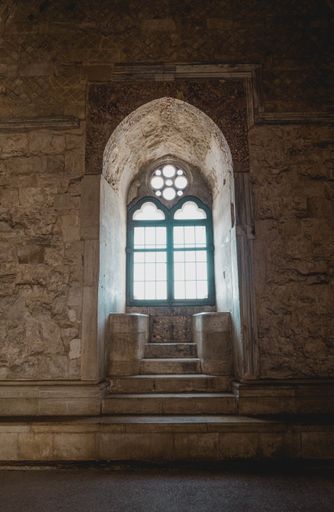 a vertical shot of the engraved arch window with stairs of Castel del Monte Andria inside in Italy