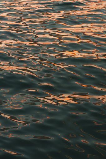 A vertical shot of a water surface with a sunset reflection