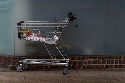 A mall pushcart with the trash left on side of a street