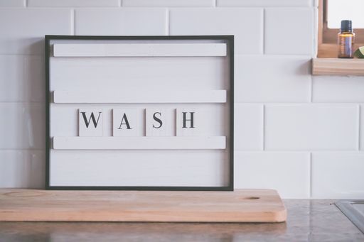 A closeup shot of a "Wash" sign raising awareness of the existing pandemic, on a white tile background