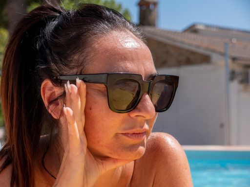 A closeup shot of a caucasian female wearing sunglasses posing near a pool