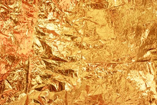 A closeup shot of a crumpled golden candy wrapper