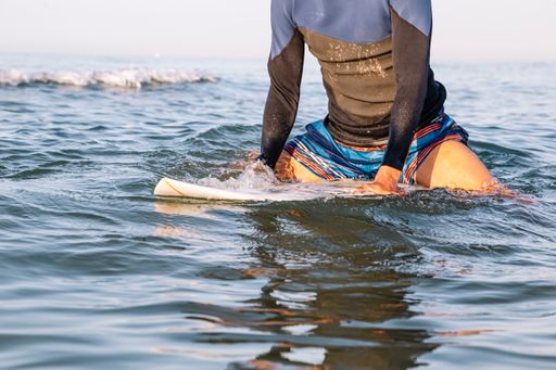 A young black surfer sitting on his surfboard in the sea water