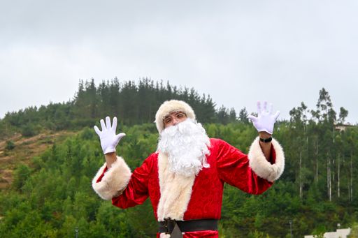 A young male in a Santa Claus suit doing a funny pose outdoors