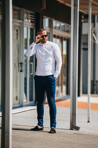 A man standing on the street wearing sunglasses with the blurred background