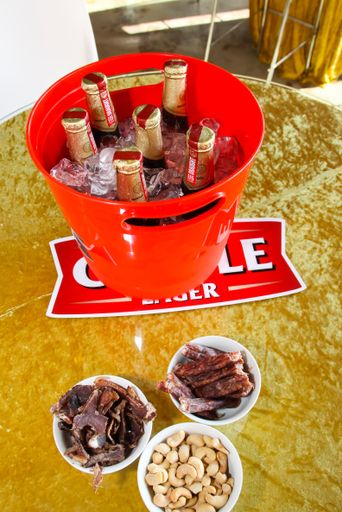 A vertical shot of Castle beer bottles in a bucket with nuts and biltong