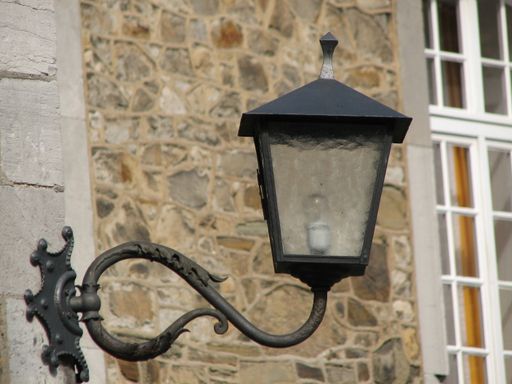 A view of a lantern hanging from the pole on the wall in the street