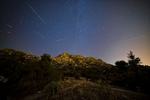 A closeup shot of a small hill under the starry night with falling stars