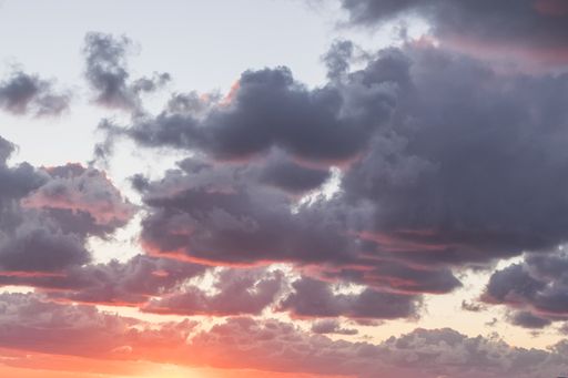 Rows of reddish low clouds during a peaceful sunset. Thick clouds and blue sky.