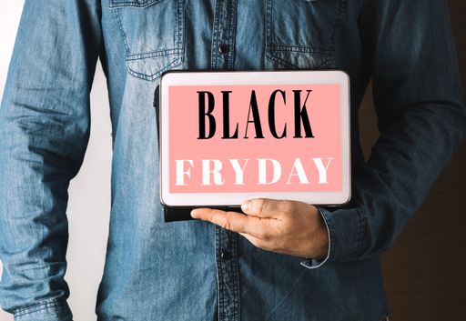 A closeup shot of a male holding a tablet with a Black Friday discount sign