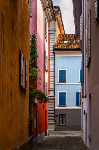 A vertical shot of colorful houses lined along a picturesque cobbled alley in Locarno Old town, Canton Ticino, Switzerland