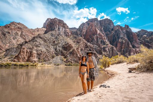 A beautiful shot of a couple together near the Colorado River in the Grand Canyon under a blue sky